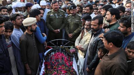 Menschen stehen neben der Leiche eines Mannes, der nach Angaben der Polizei am 13. Februar 2022 im Dorf Tulamba in Zentralpakistan von einem Mob kurzerhand hingerichtet wurde.