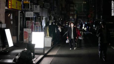 Menschen gehen während eines Stromausfalls in Tokio eine Straße entlang.