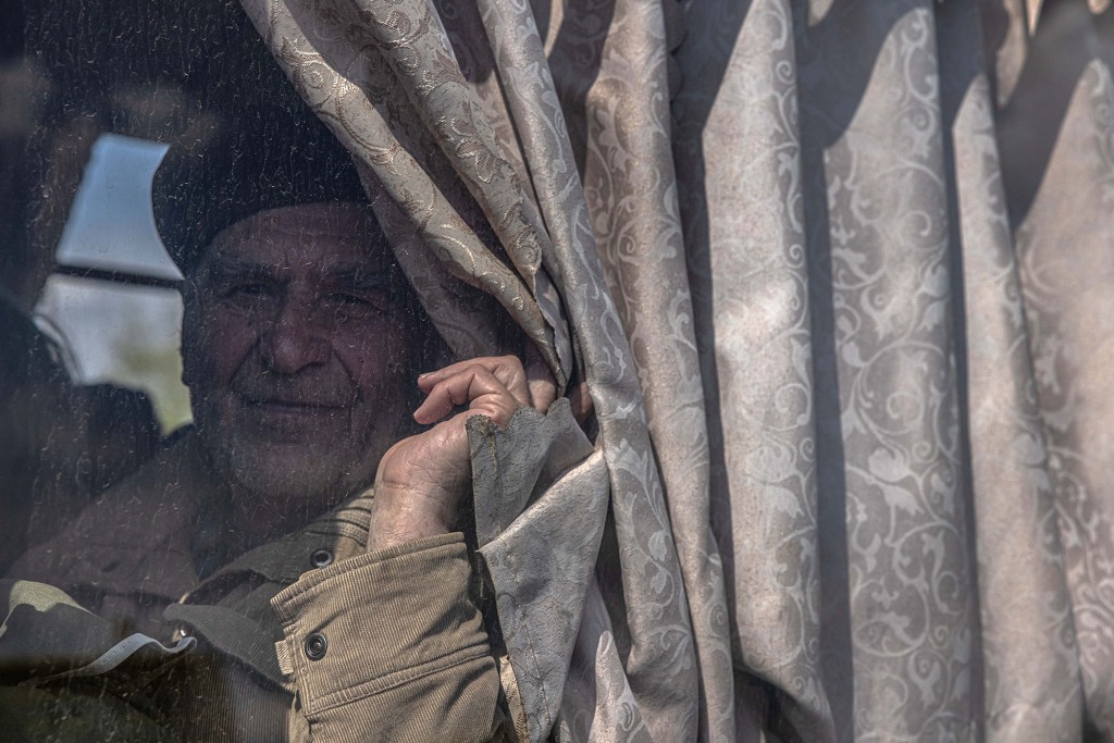 Ein älterer Mann sieht ihn an, als er in einem Bus sitzt, nachdem er aus der Frontstadt Urekiew am Evakuierungspunkt in Zaporizhia, Ukraine, angekommen ist