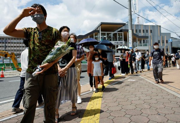 An der Stelle, an der Shinzo Abe verletzt wurde, stehen Menschen Schlange, um Blumen zu verteilen und zu beten