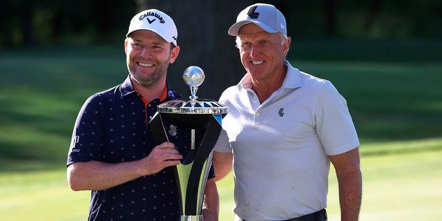 Branden Grace, links, und Greg Norman, CEO von LIV Golf, rechts, stehen mit der Trophäe, nachdem Grace die Portland Invitational LIV Golf Championship in North Plains, Oregon, am 2. Juli 2022 gewonnen hat. 