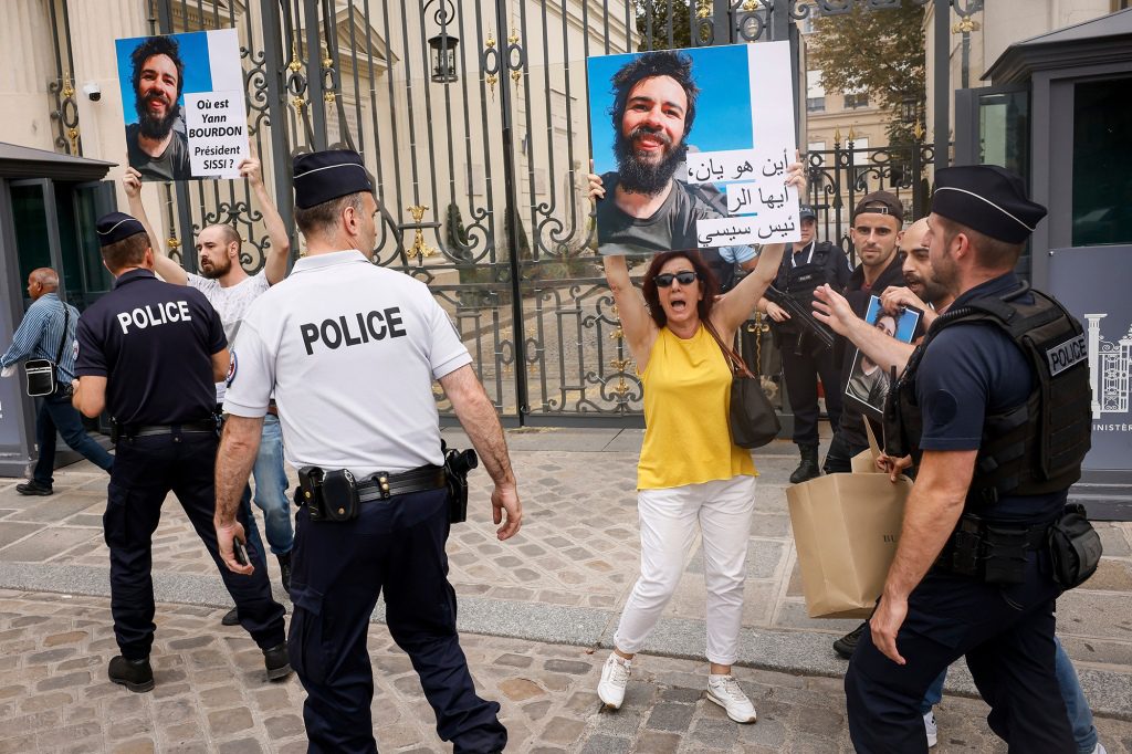 Die Familie und Freunde des Studenten standen auf einem Bürgersteig in Paris und hielten Schilder mit der Bitte hoch 