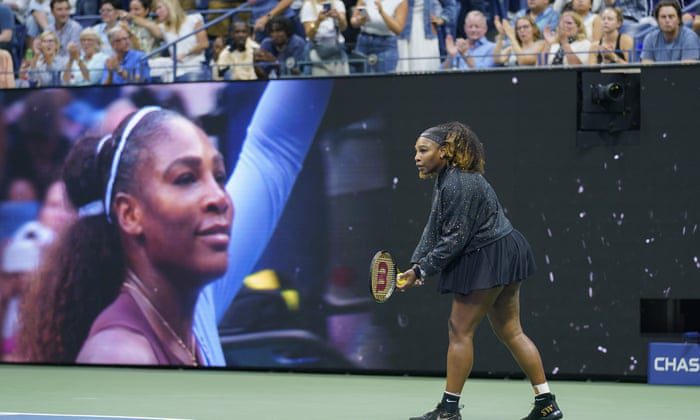 Serena Williams bereitet sich darauf vor, sich vor einem großen Bildschirm aufzuwärmen, der sie auf dem Platz willkommen heißt.
