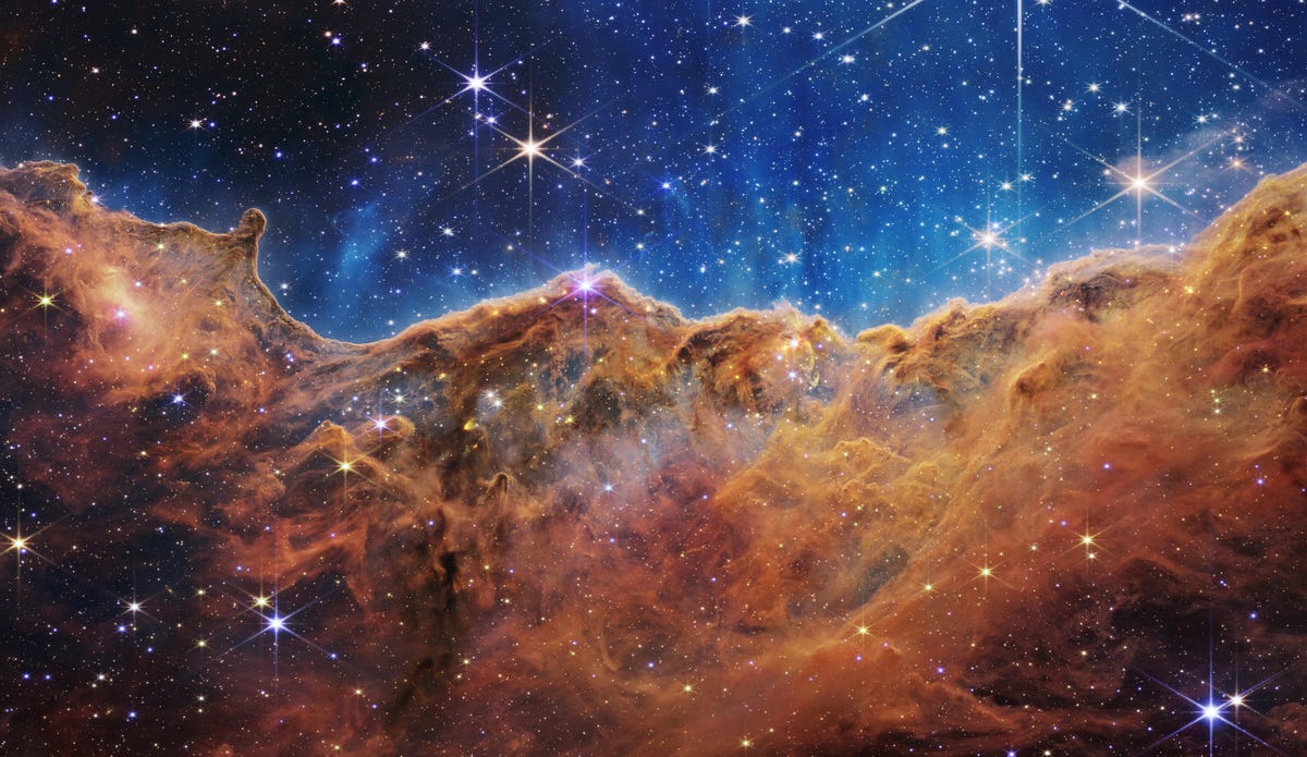 Der Carina-Nebel: Sterne funkeln vor einem indigoblauen Hintergrund über rostigen bronzefarbenen Gaswolken